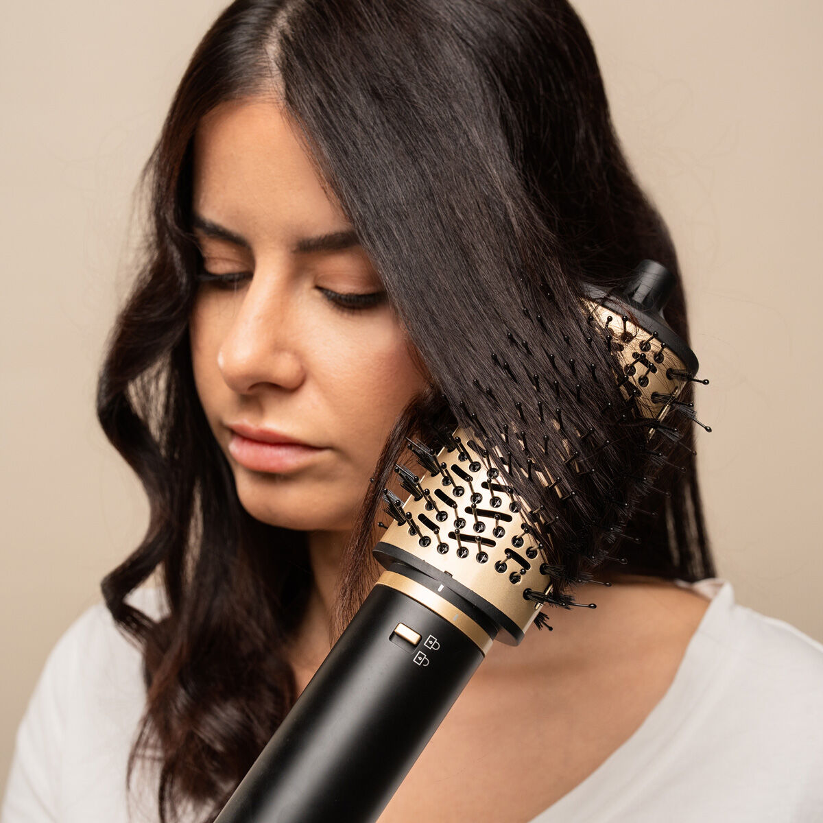 Brosse soufflante en action dans une chevelure brune, de profil