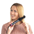 Femme blonde souriante passant la brosse lissante dans ses cheveux, sur fond blanc détouré